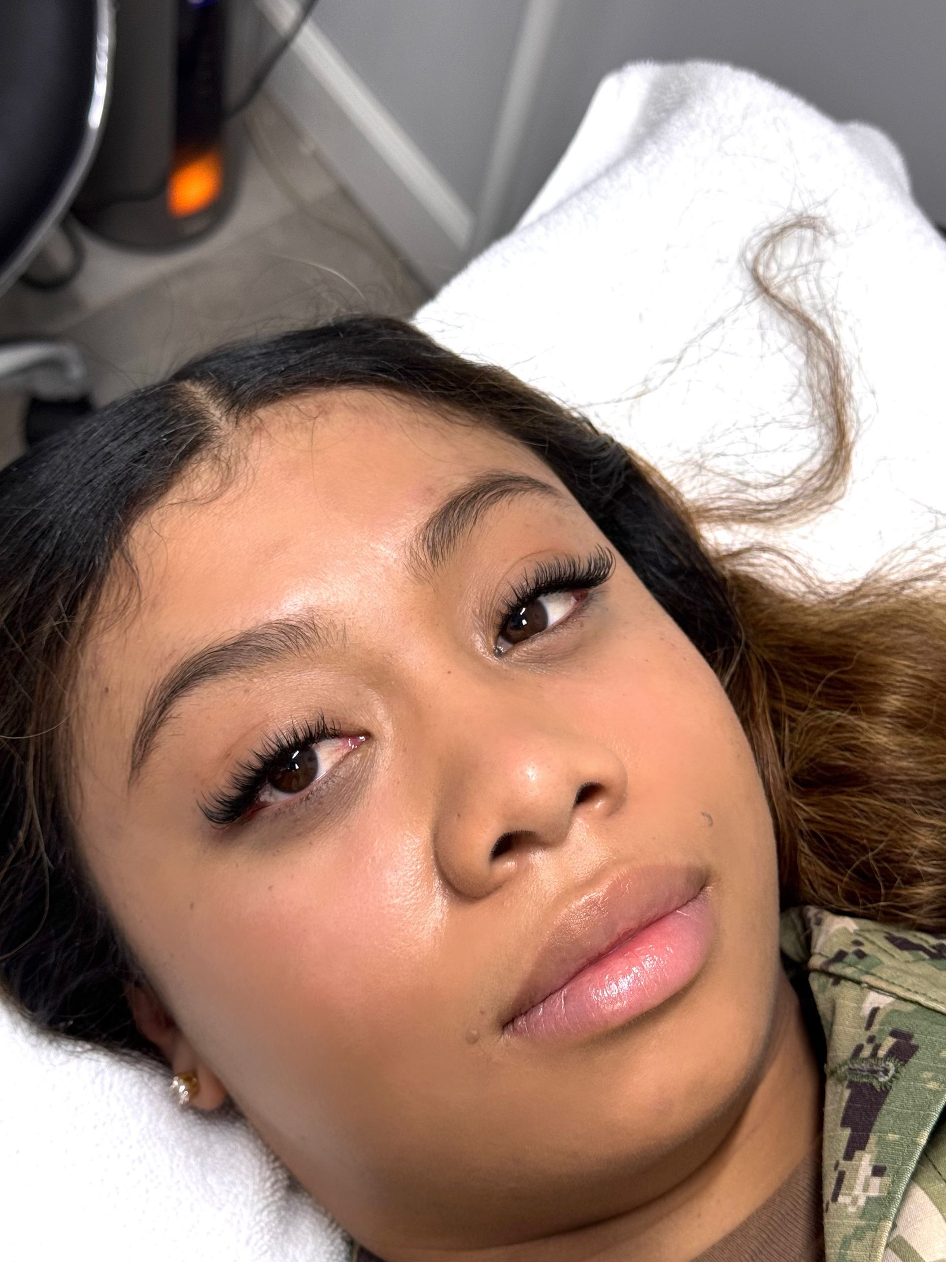 Woman with eyelash extensions, lying down, looking at the camera.