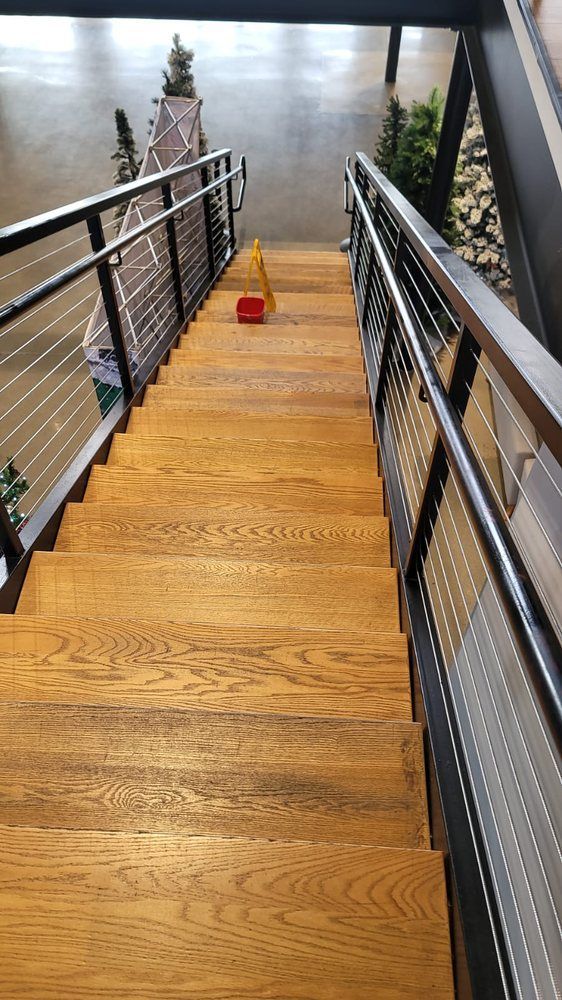 Wooden staircase with metal railings, a caution cone is on the steps.