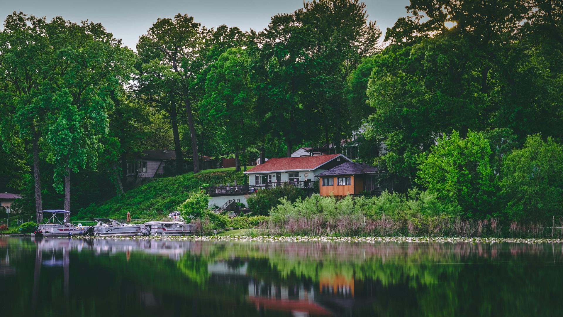 A house is sitting on the shore of a lake surrounded by trees.