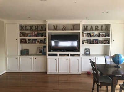 A living room with a table , chairs , shelves and a flat screen tv