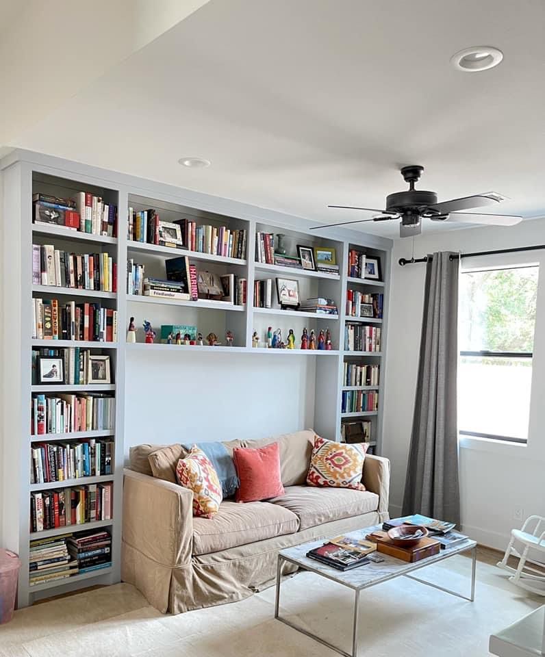 A living room with a couch , coffee table , and shelves filled with books