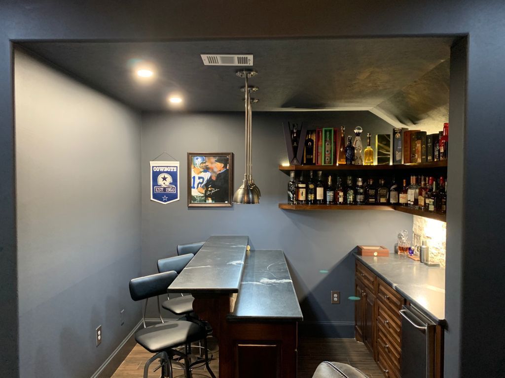 A room with a bar and a lot of bottles on shelve