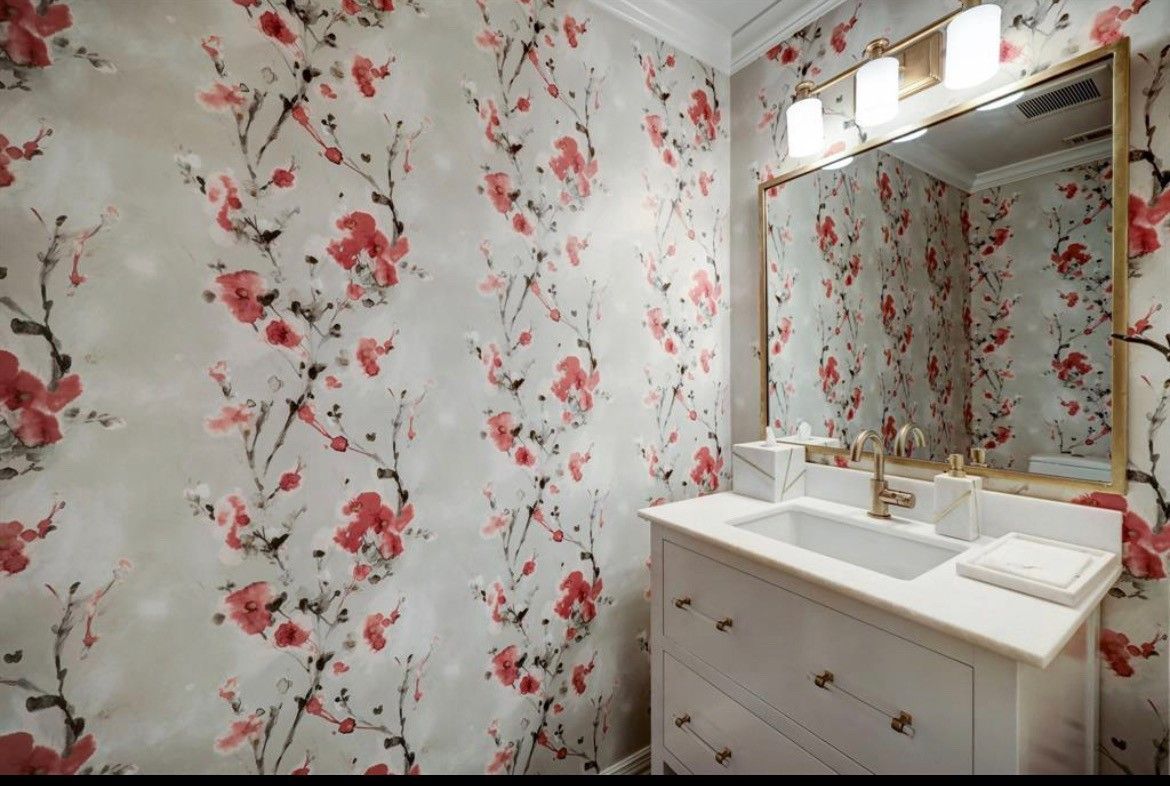 A bathroom with  sink , mirror and floral wallpaper.