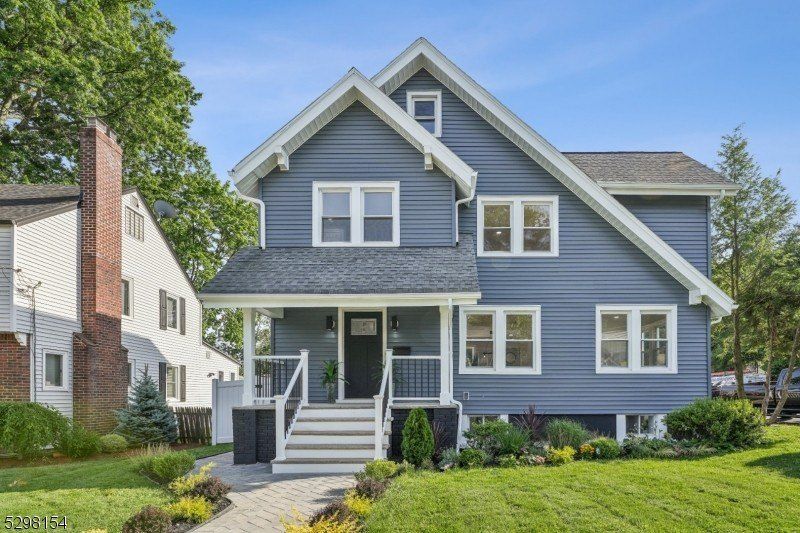 Blue house with white trim, a porch, and chimney on a sunny day.