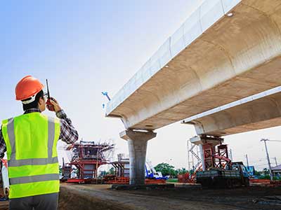 un uomo con un giubbotto fluorescente accanto a un ponte nella fase di costruzione