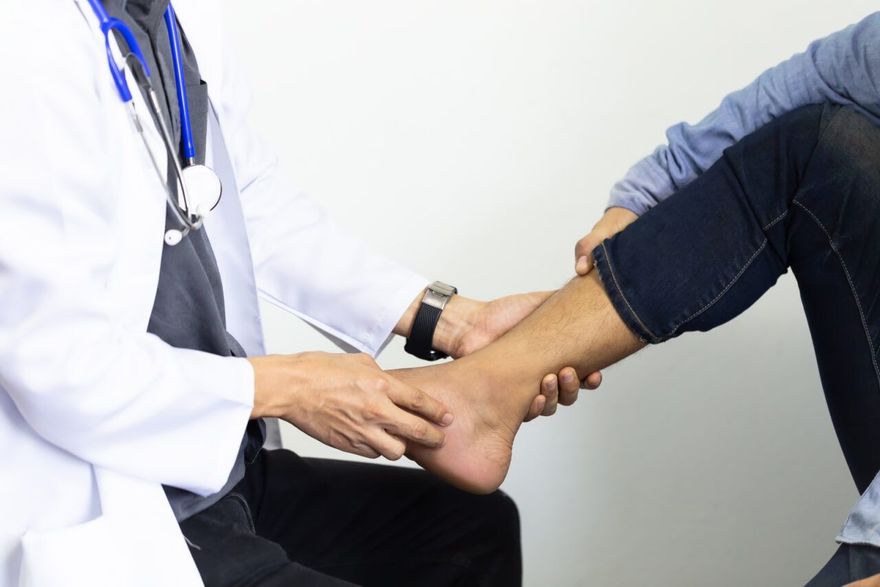 Doctor Examining a Patient's Ankle, White Lab Coat and Stethoscope Visible — Tewantin Medical Centre In Tewantin, QLD