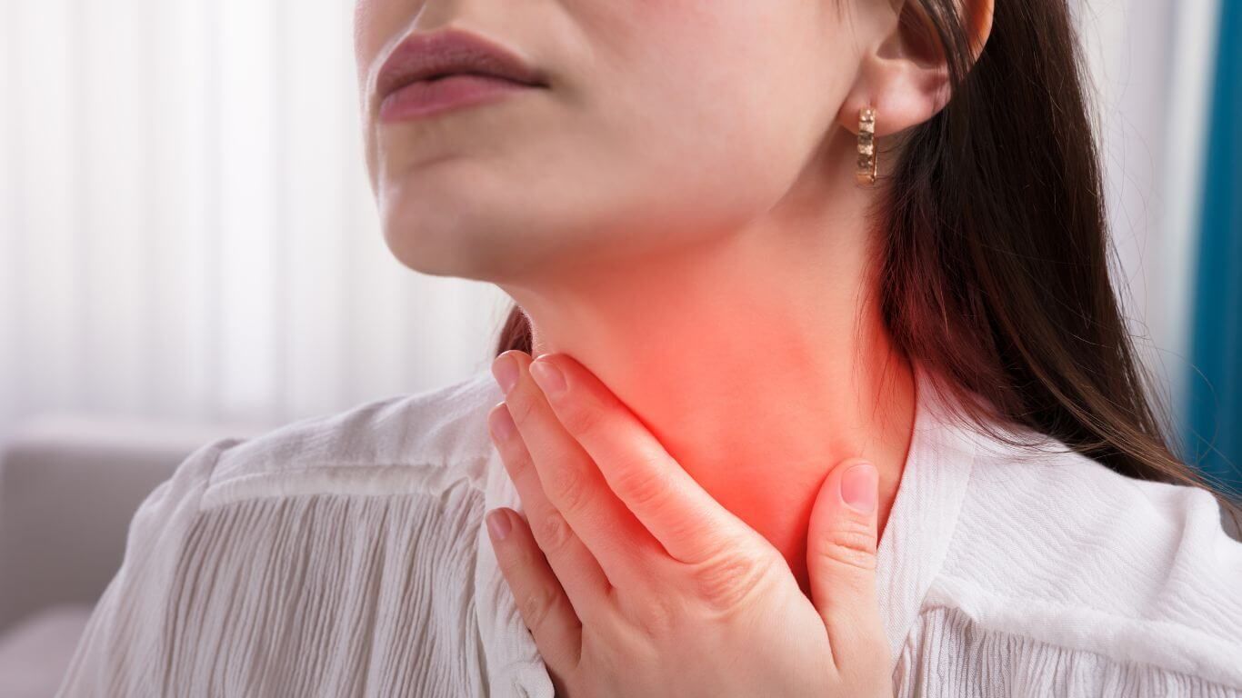 Woman Holding Her Neck With a Pained Expression, Indicating a Sore Throat — Tewantin Medical Centre In Tewantin, QLD