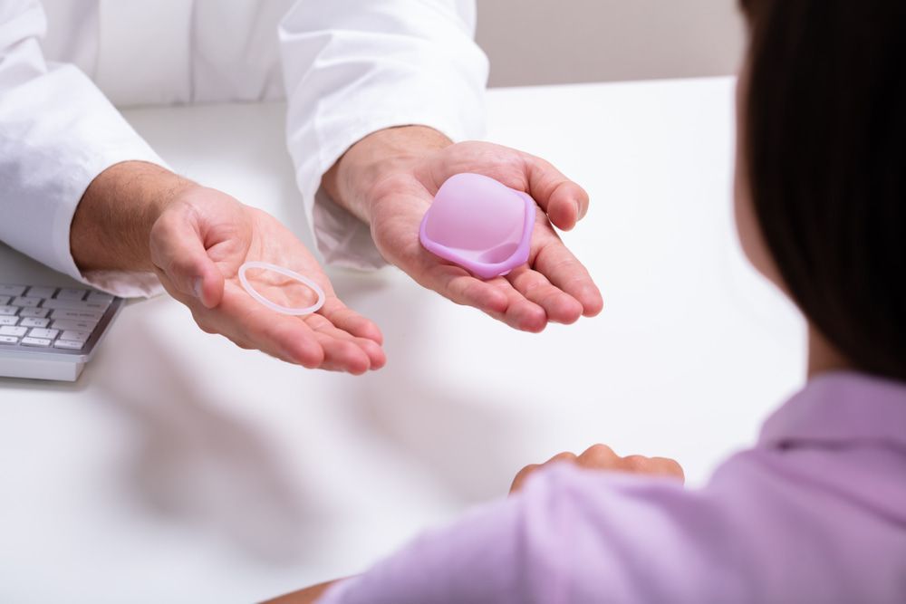 Doctor Holding Vaginal Ring and Diaphragm, Explaining Options to Patient