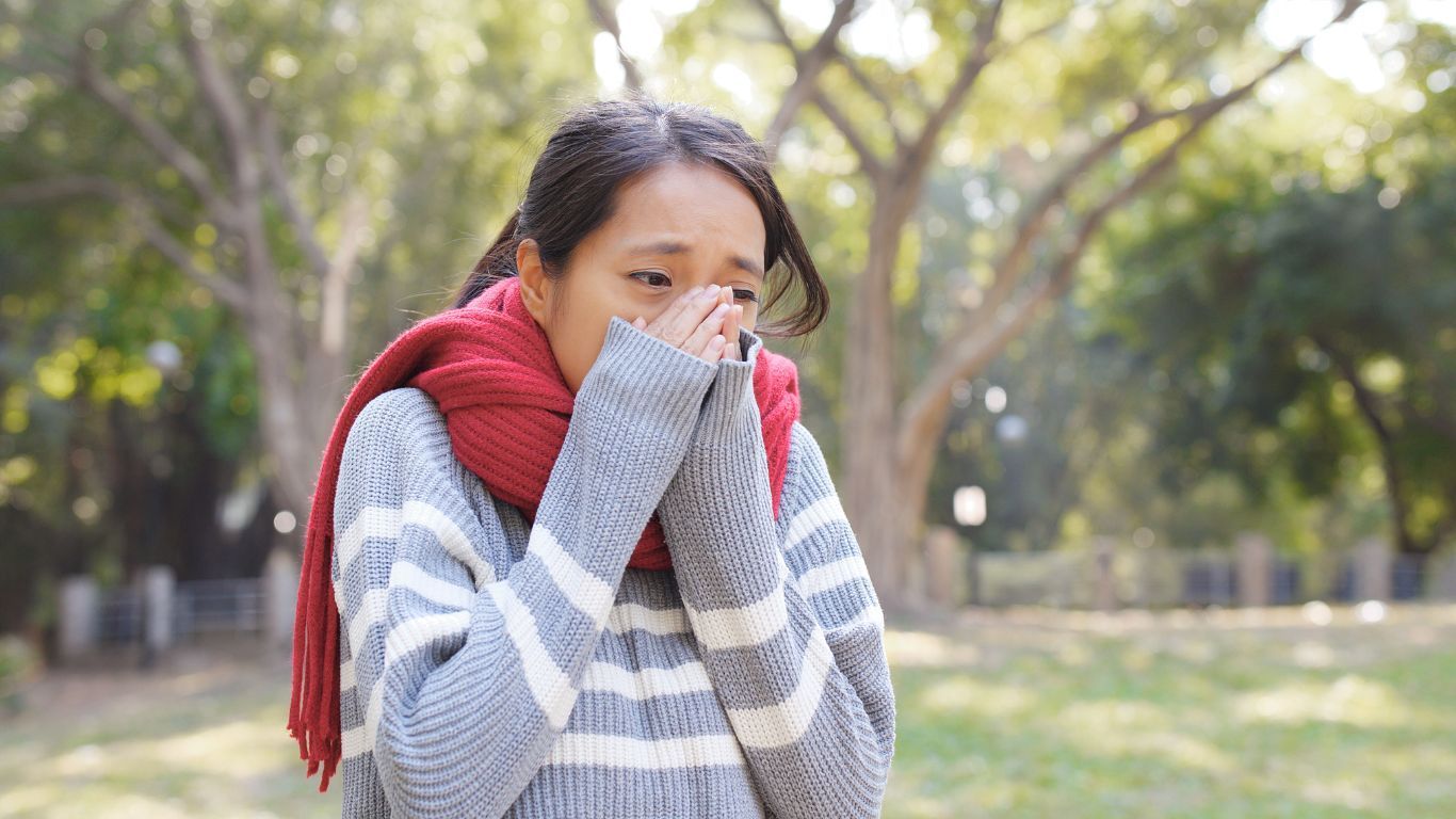 Woman in a Red Scarf and Sweater, Covering Her Face in a Park — Tewantin Medical Centre In Tewantin, QLD