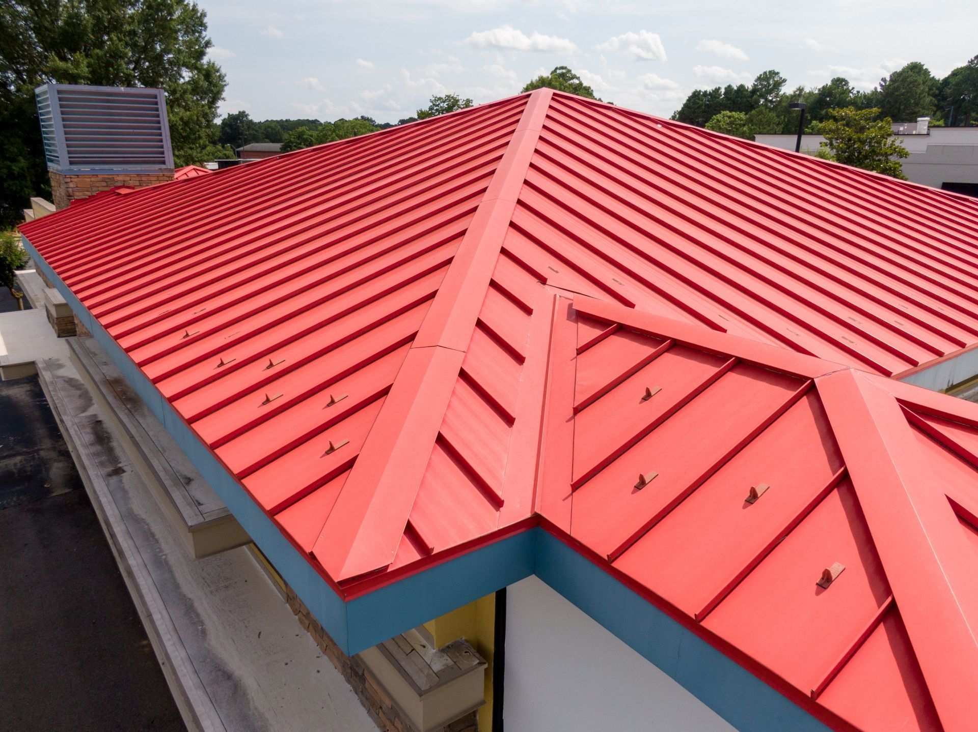 Bright red metal roof on a building with a blue trim. Sunny day, exterior shot.