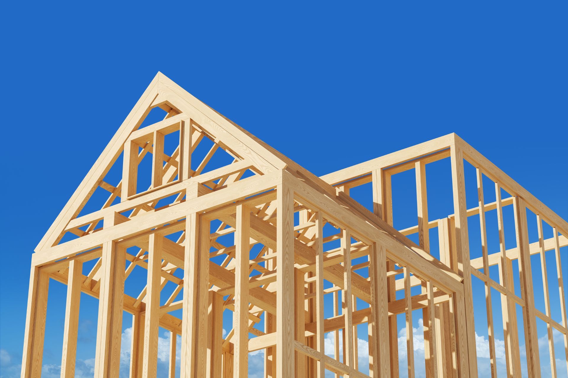 Wooden framework of a house against a blue sky, showcasing construction stage.