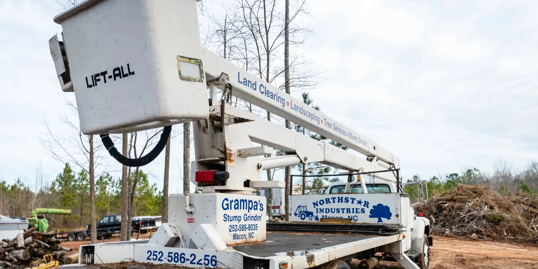A white truck with a lift on top of it is parked in a field.