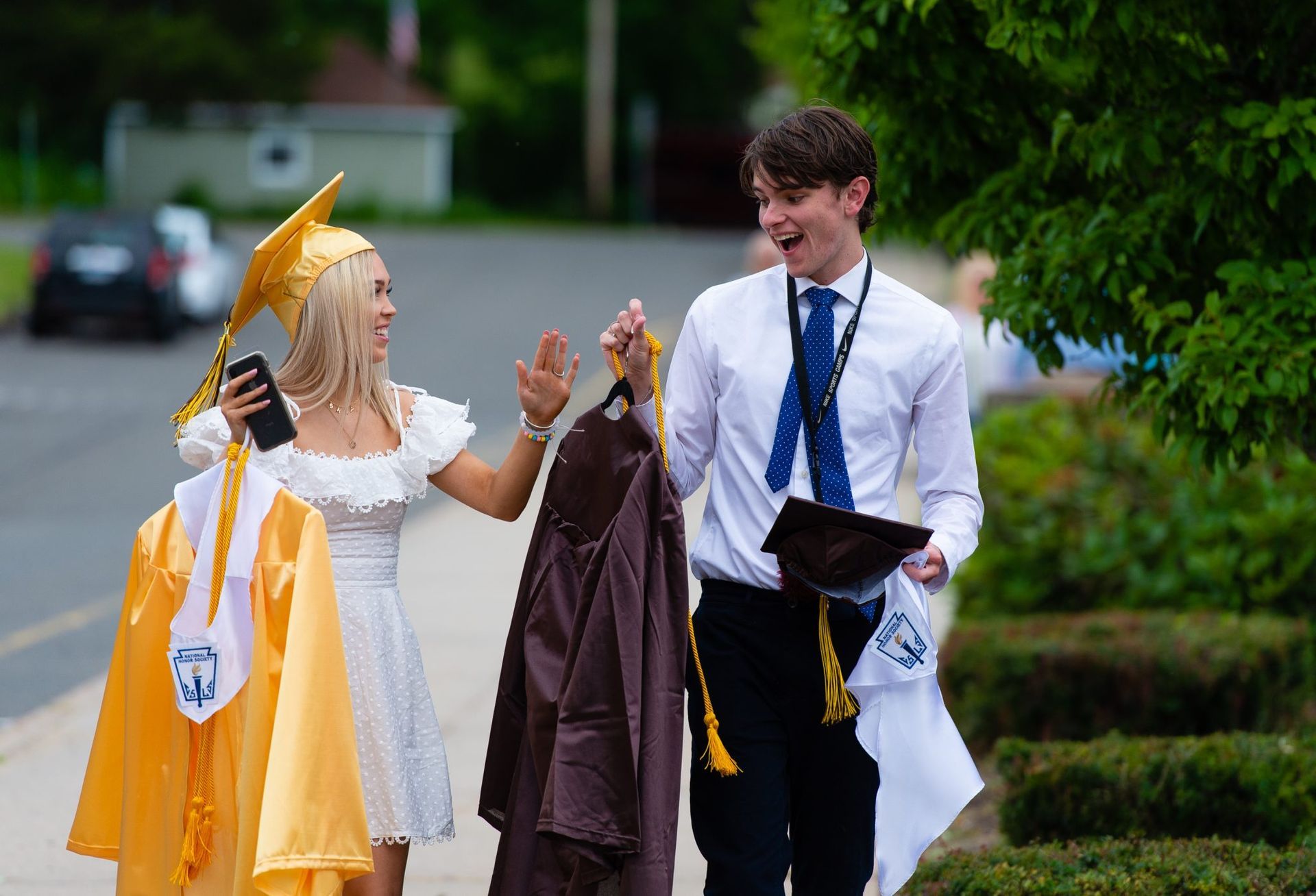 a man and a woman in graduation caps and gowns are walking down a sidewalk .