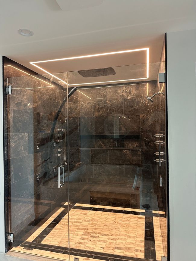 A bathroom with a glass shower door and a marble floor.