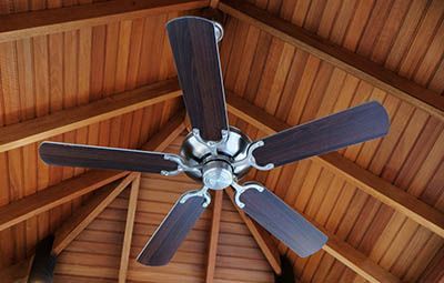 A ceiling fan is hanging from the ceiling of a wooden building.