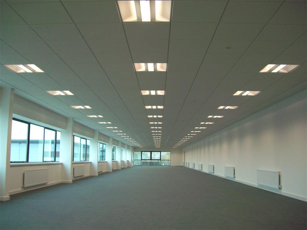 A large empty room with a lot of windows and ceiling lights