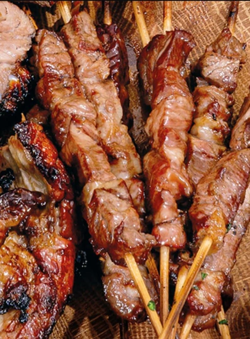 Spiedini di carne alla griglia, primo piano. Carne grigliata rosolata su spiedini di legno, disposti insieme.