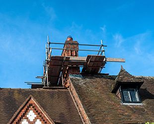 a man is standing on a scaffolding on top of a roof .