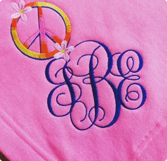 A pink shirt with a monogram and a peace sign