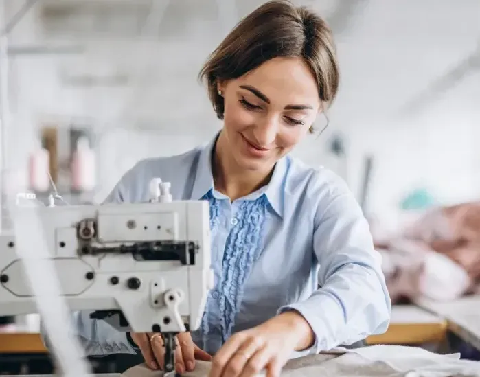 A woman is using a sewing machine in a factory.