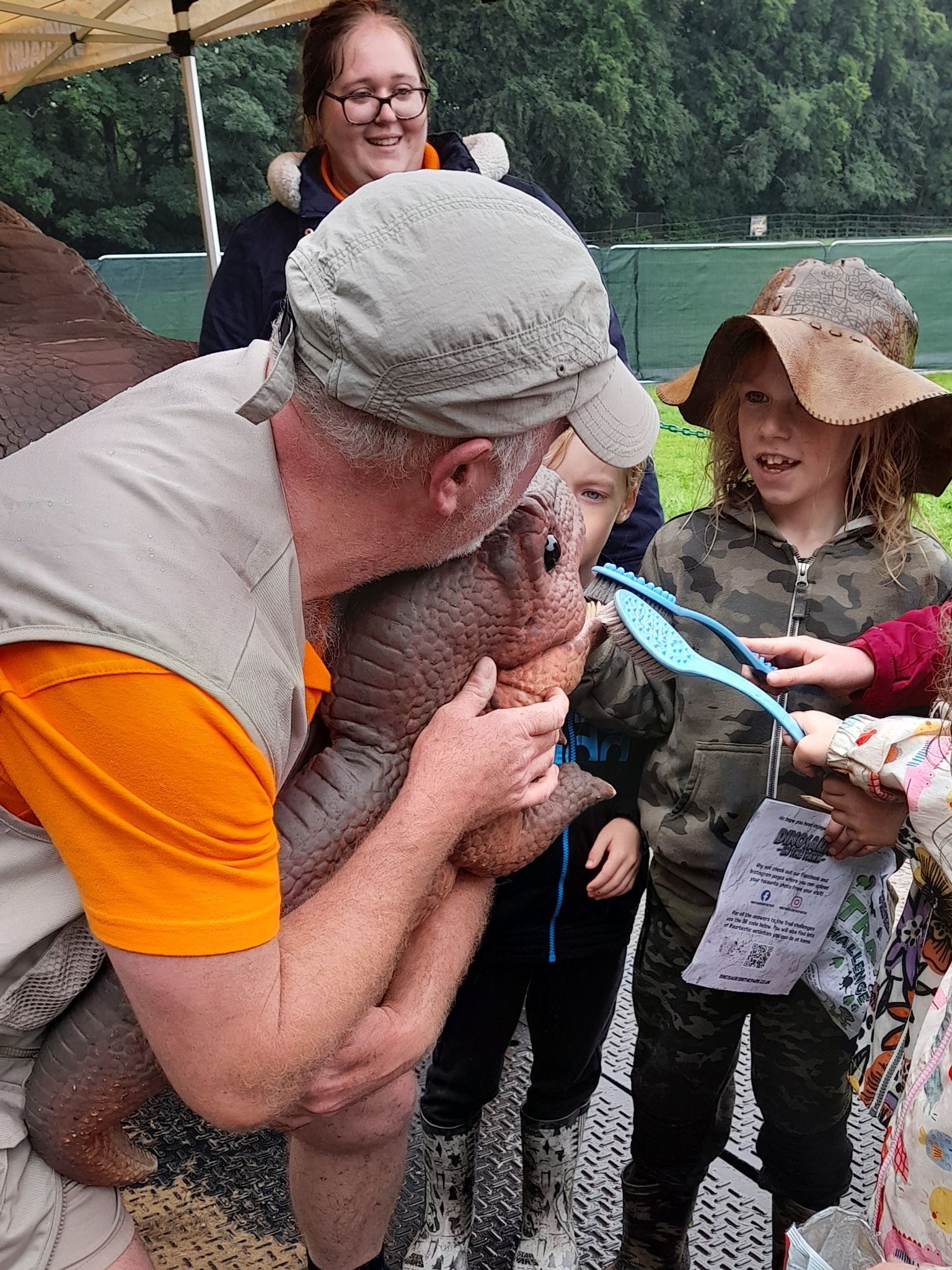A man is holding a small animal in his arms while a group of children look on.