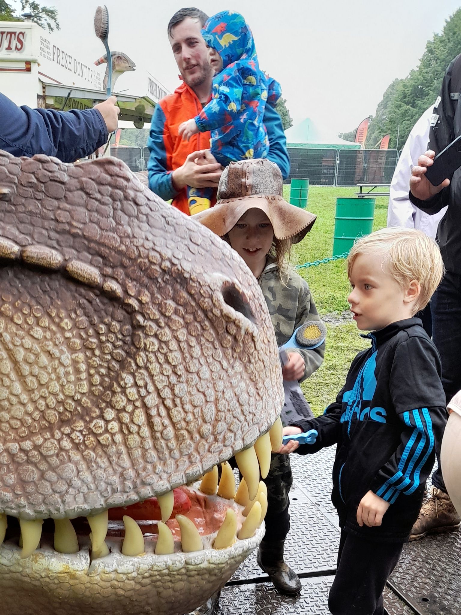 A group of people are standing around a large dinosaur head.