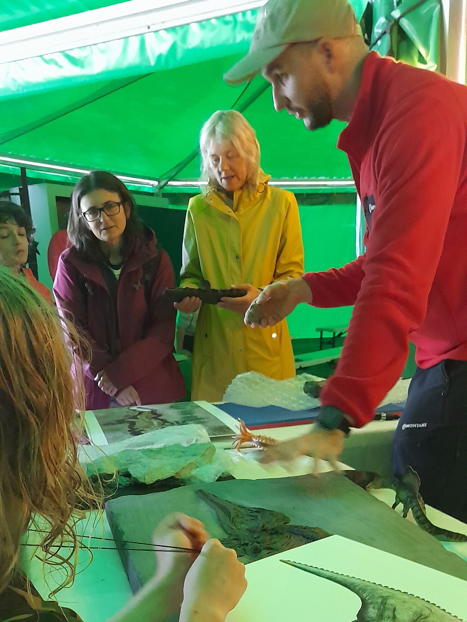 A group of people are sitting around a table under a green tent.