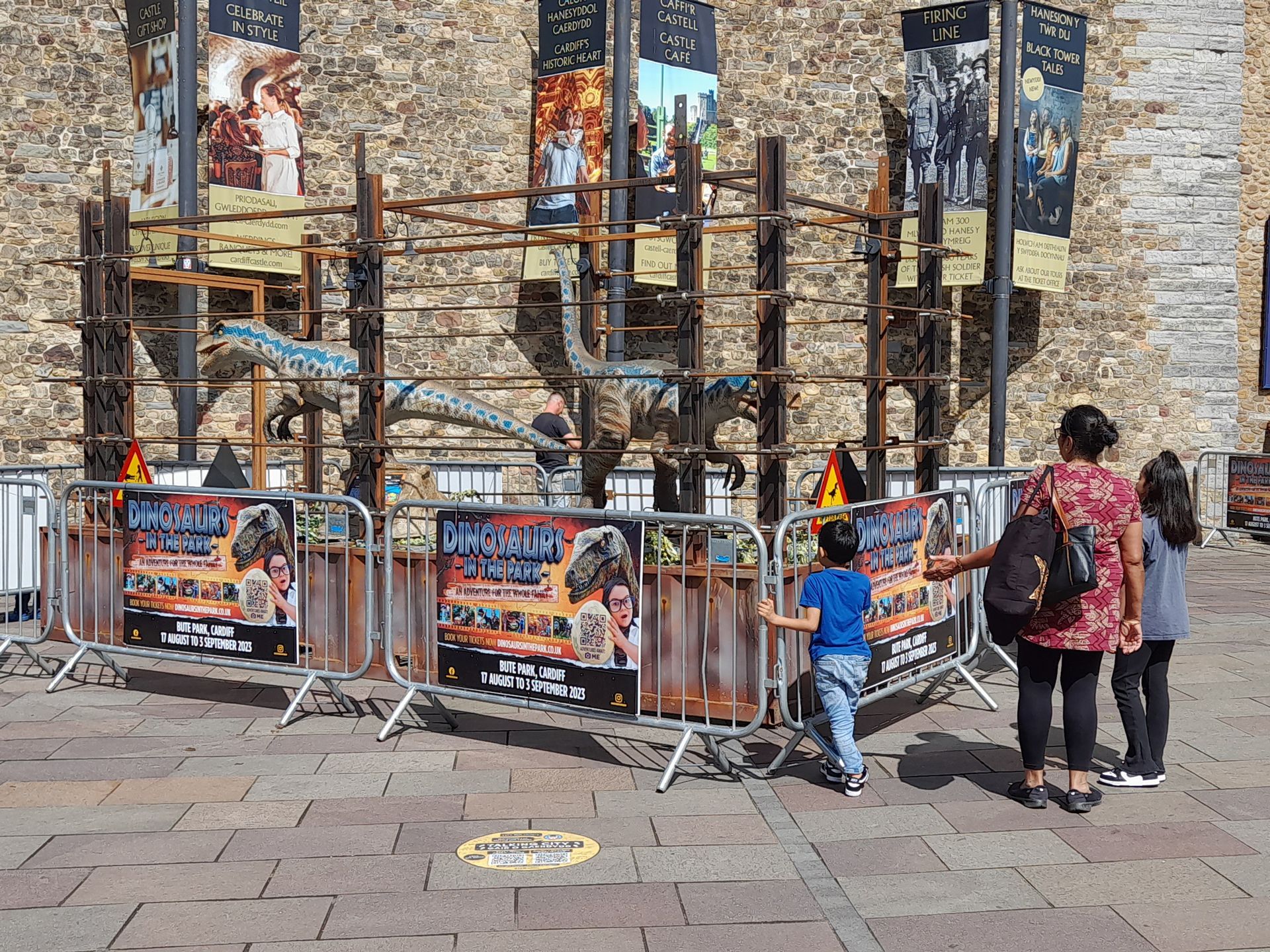 A woman and two children are standing in front of a dinosaur exhibit.