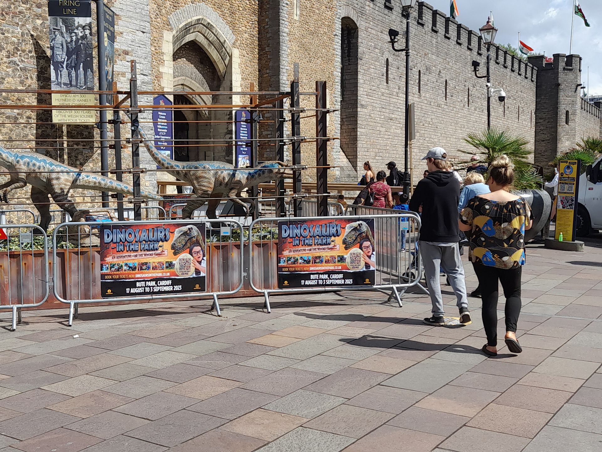 A group of people are walking down a sidewalk in front of a building.
