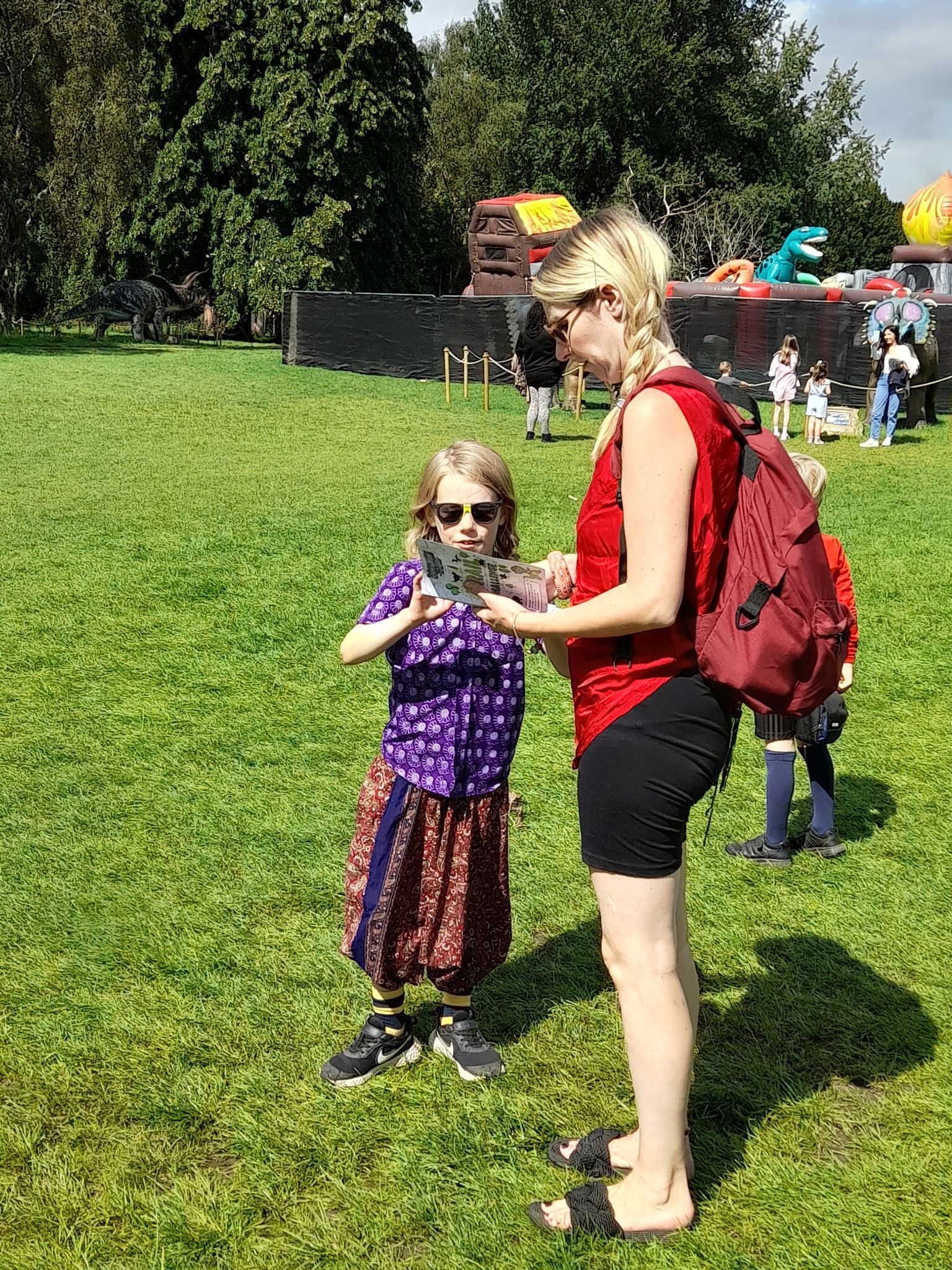 A woman is standing next to a little girl in a park.