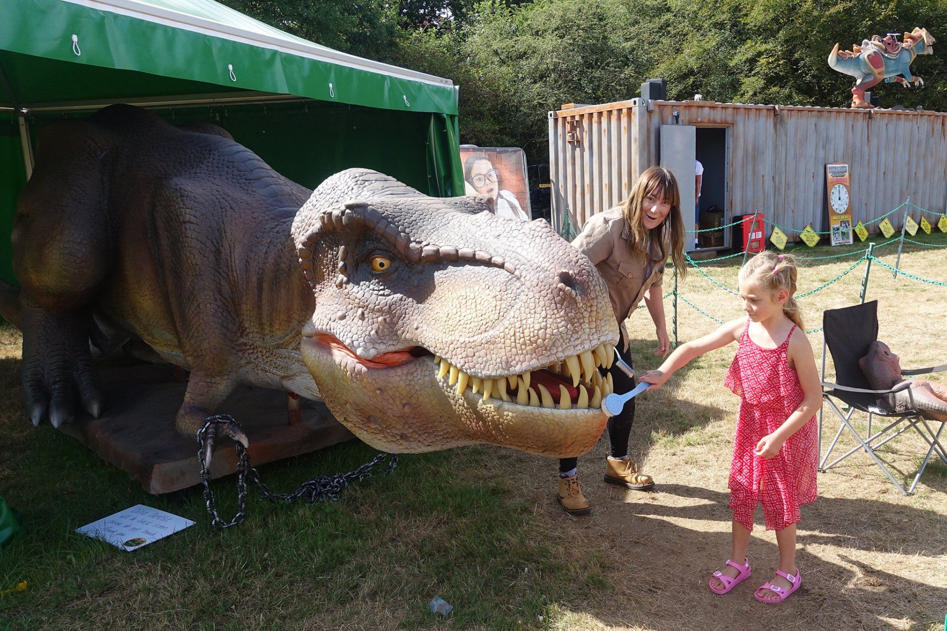 A woman and a little girl are standing next to a dinosaur model.