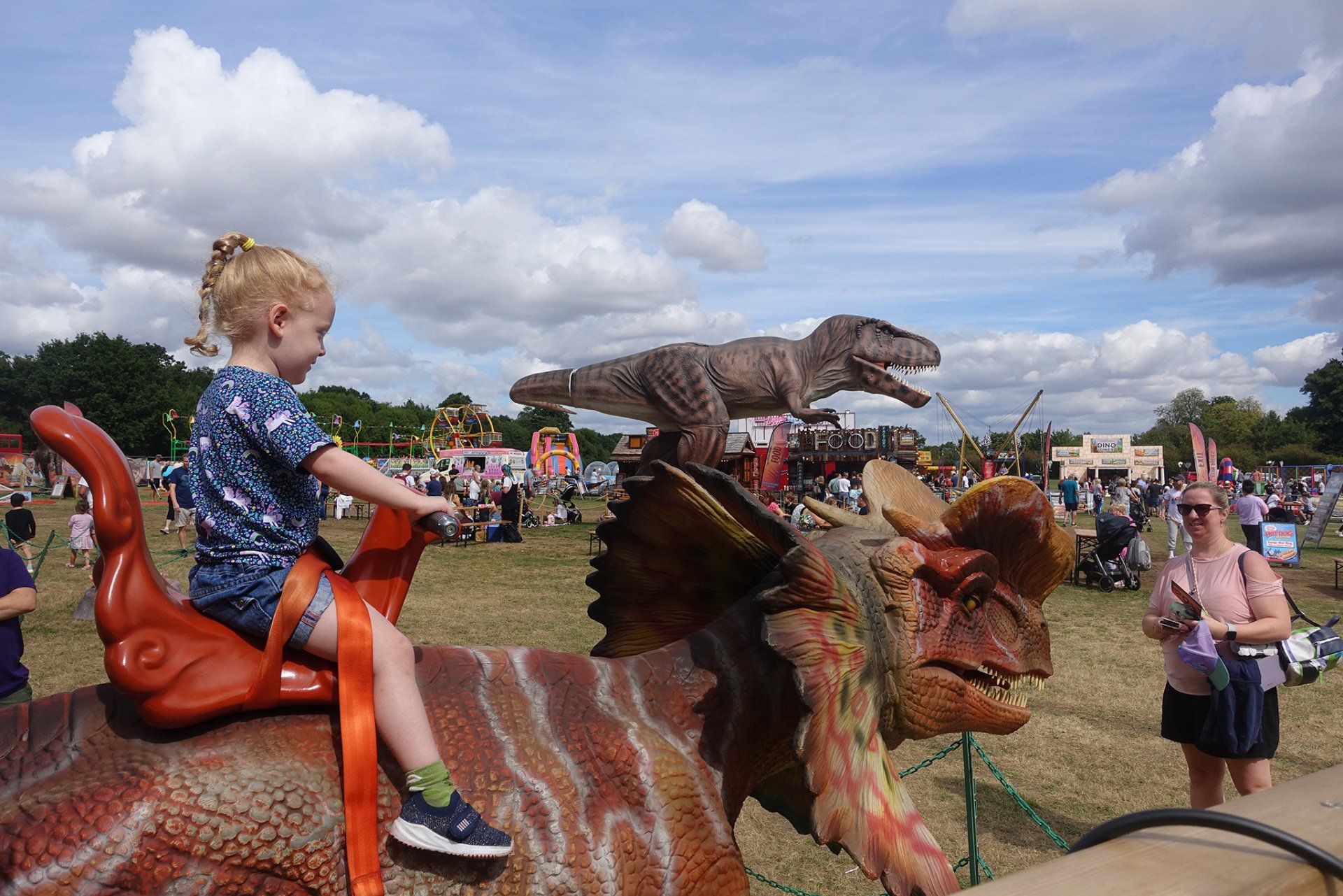 A little girl is riding on the back of a dinosaur.