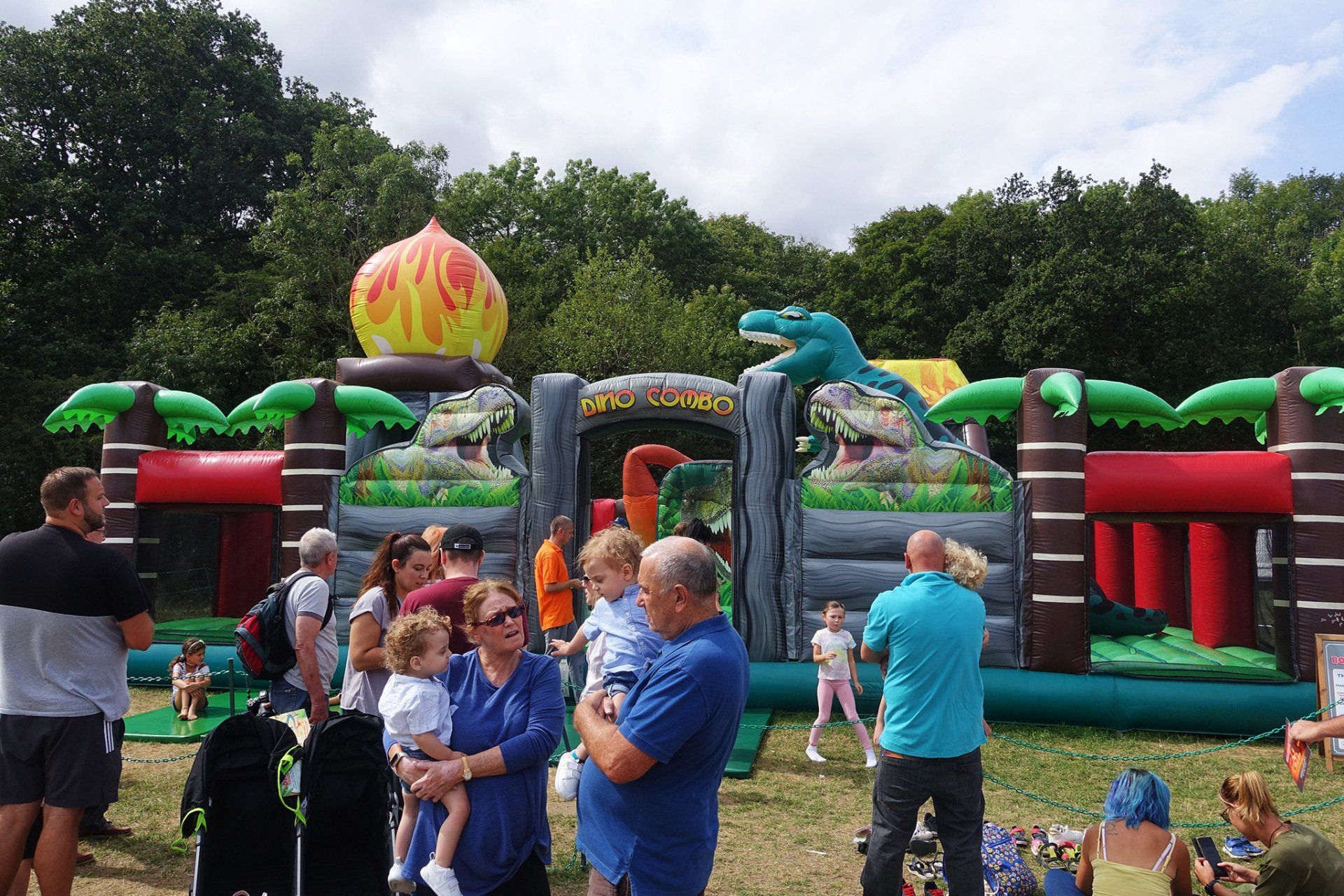 A group of people are standing in front of an inflatable dinosaur theme park.
