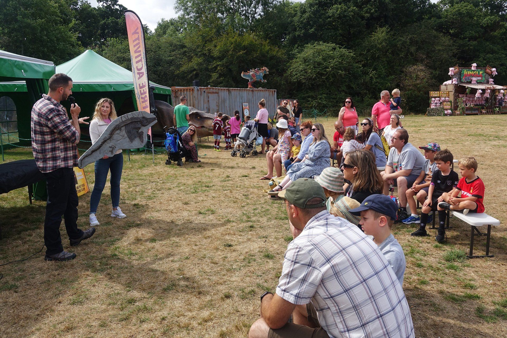 A group of people are sitting in a field watching a man holding a bird.