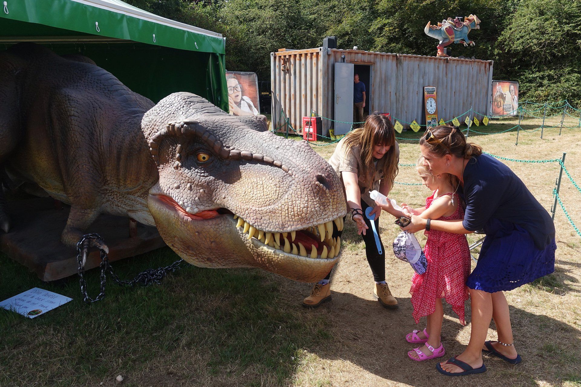A group of people are standing around a model of a dinosaur.