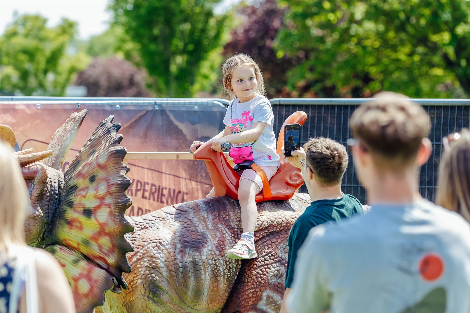 A little girl is riding on the back of a dinosaur.
