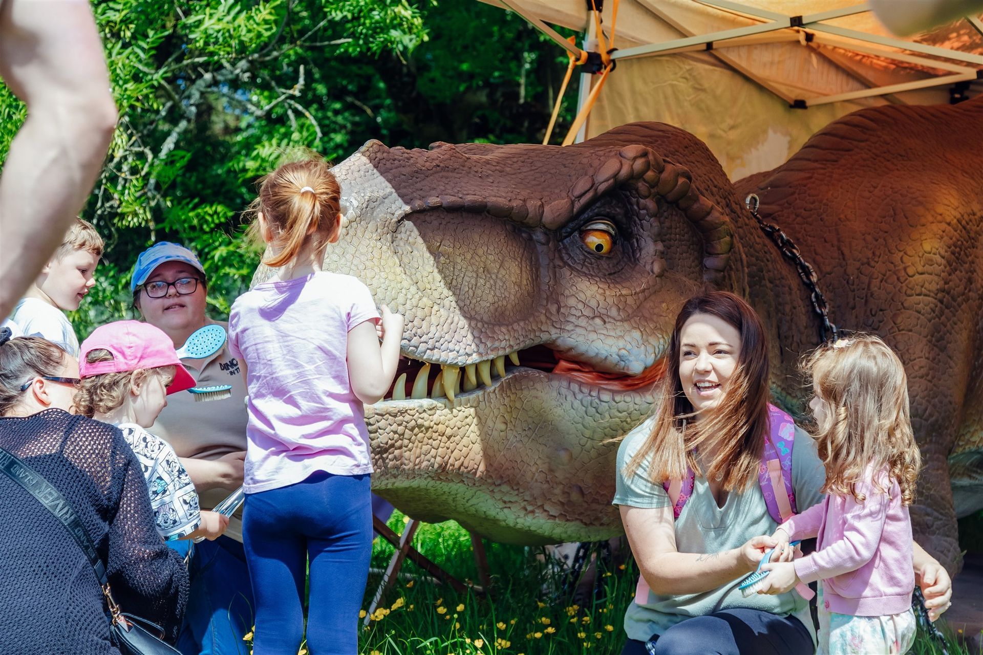 A group of people are standing around a dinosaur model.