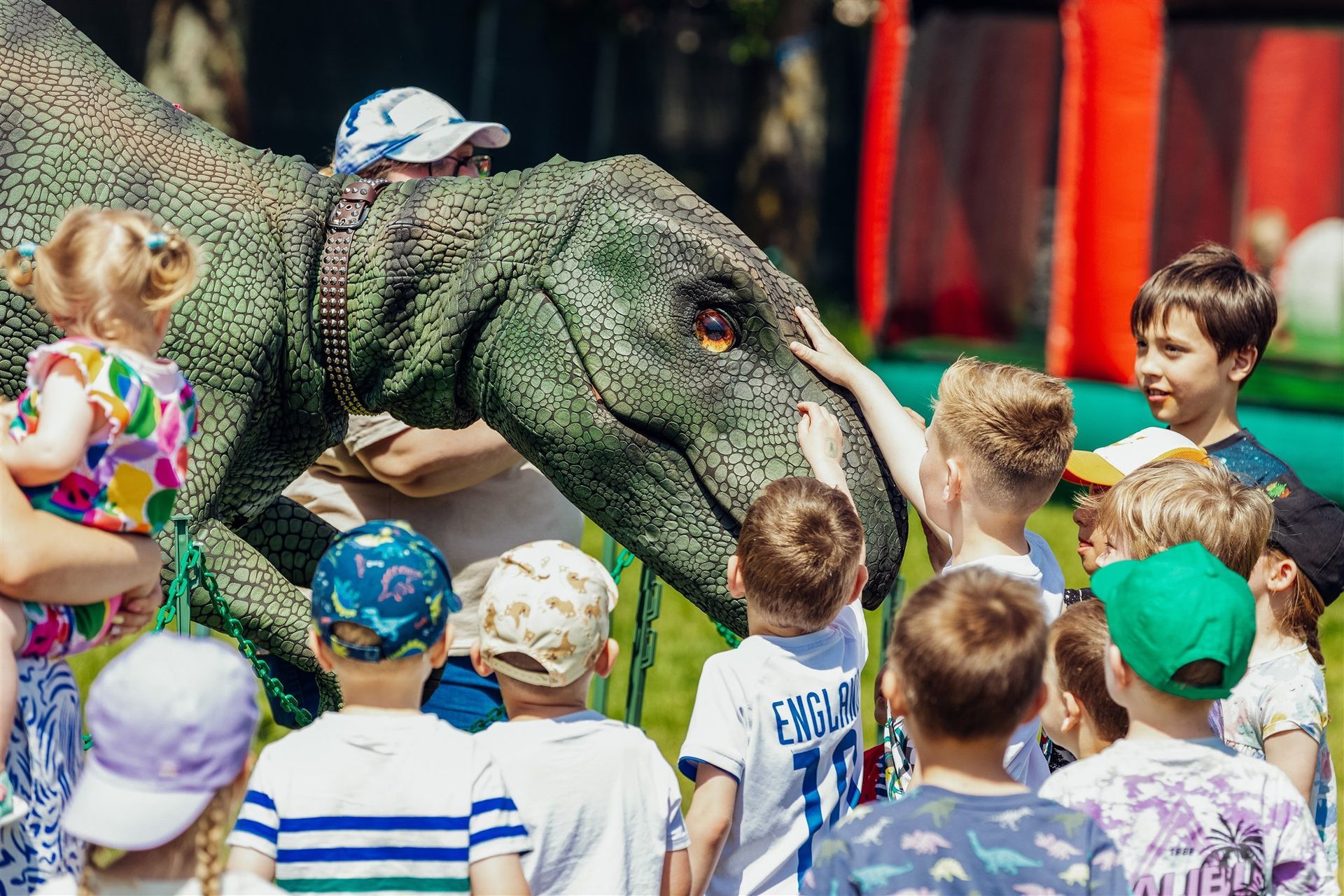 A group of children are petting a dinosaur costume.