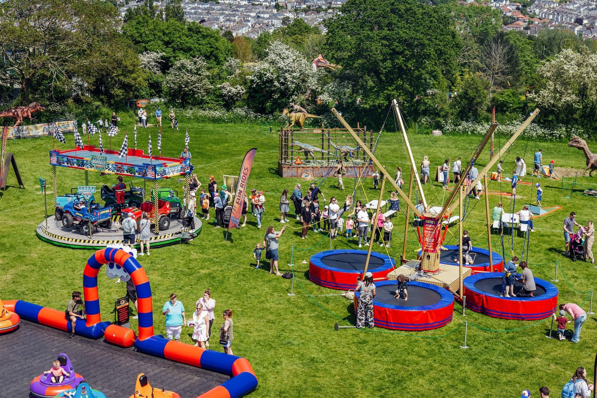 A group of people are playing in a park with trampolines and a merry go round.
