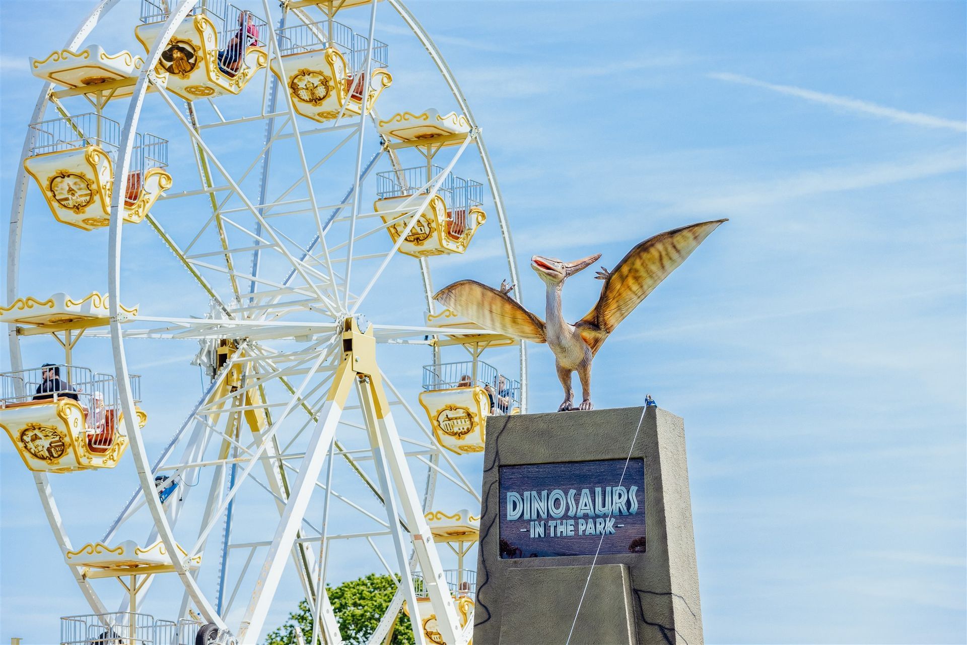 A ferris wheel with a dinosaur model in front of it.