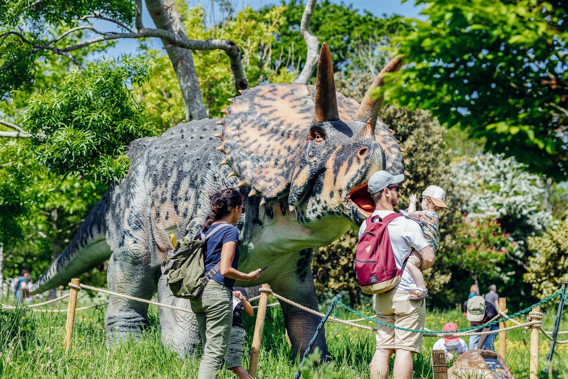 A group of people are standing in front of a dinosaur model.