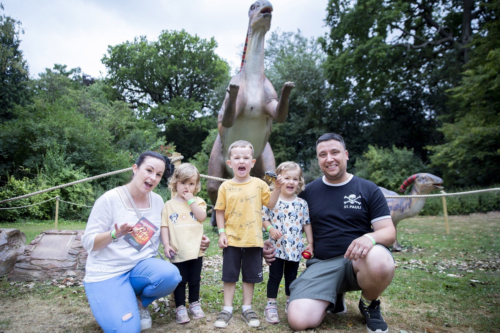 A family is posing for a picture in front of a dinosaur model.