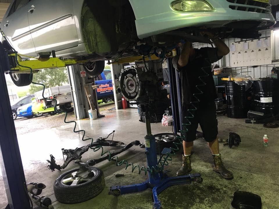 A Man is Working Under a Car on a Lift in a Garage — Zilzie Workshop In Emu Park, QLD