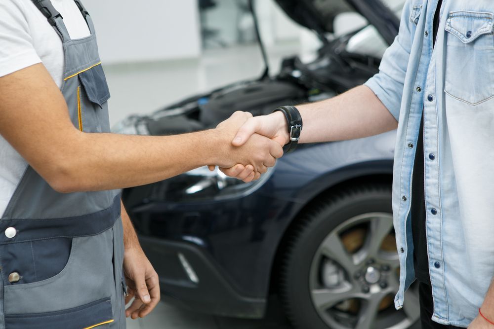 A Man is Shaking Hands With a Mechanic in Front of a Car — Zilzie Workshop In Emu Park, QLD