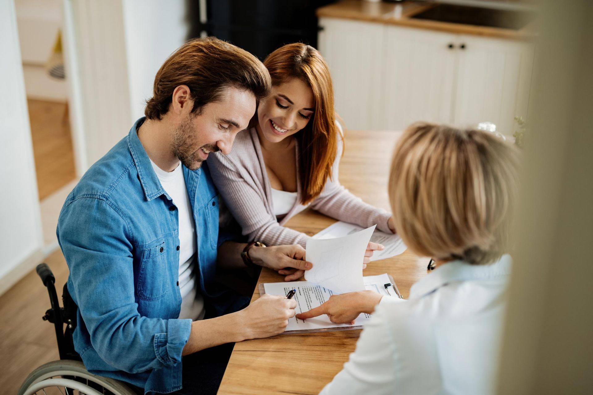 Two people reviewing documents with a consultant at a table in a bright office