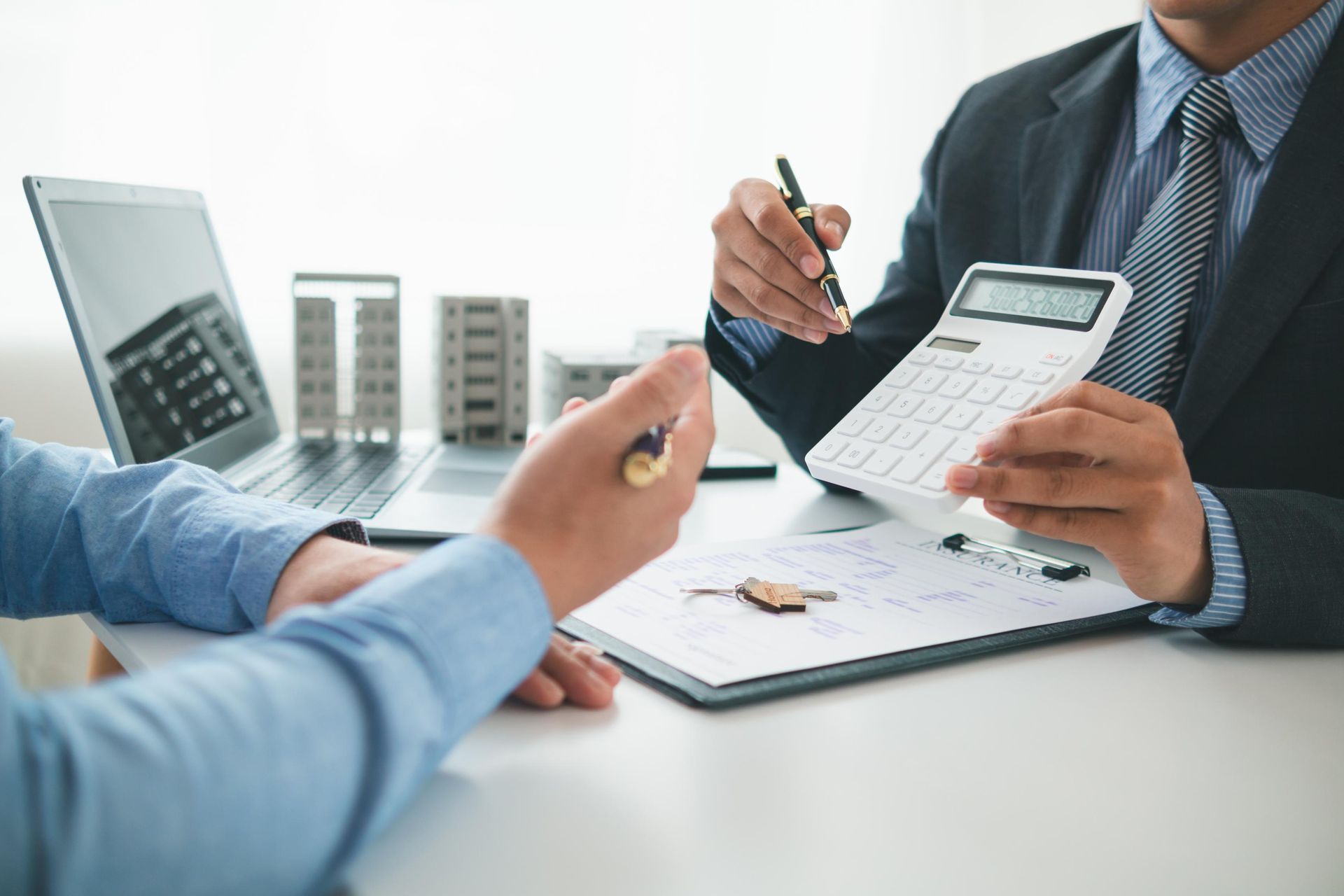 Business meeting with people reviewing documents, using a calculator and pen at a desk.