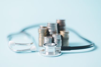 A stethoscope beside stacked coins, suggesting medical costs or healthcare savings