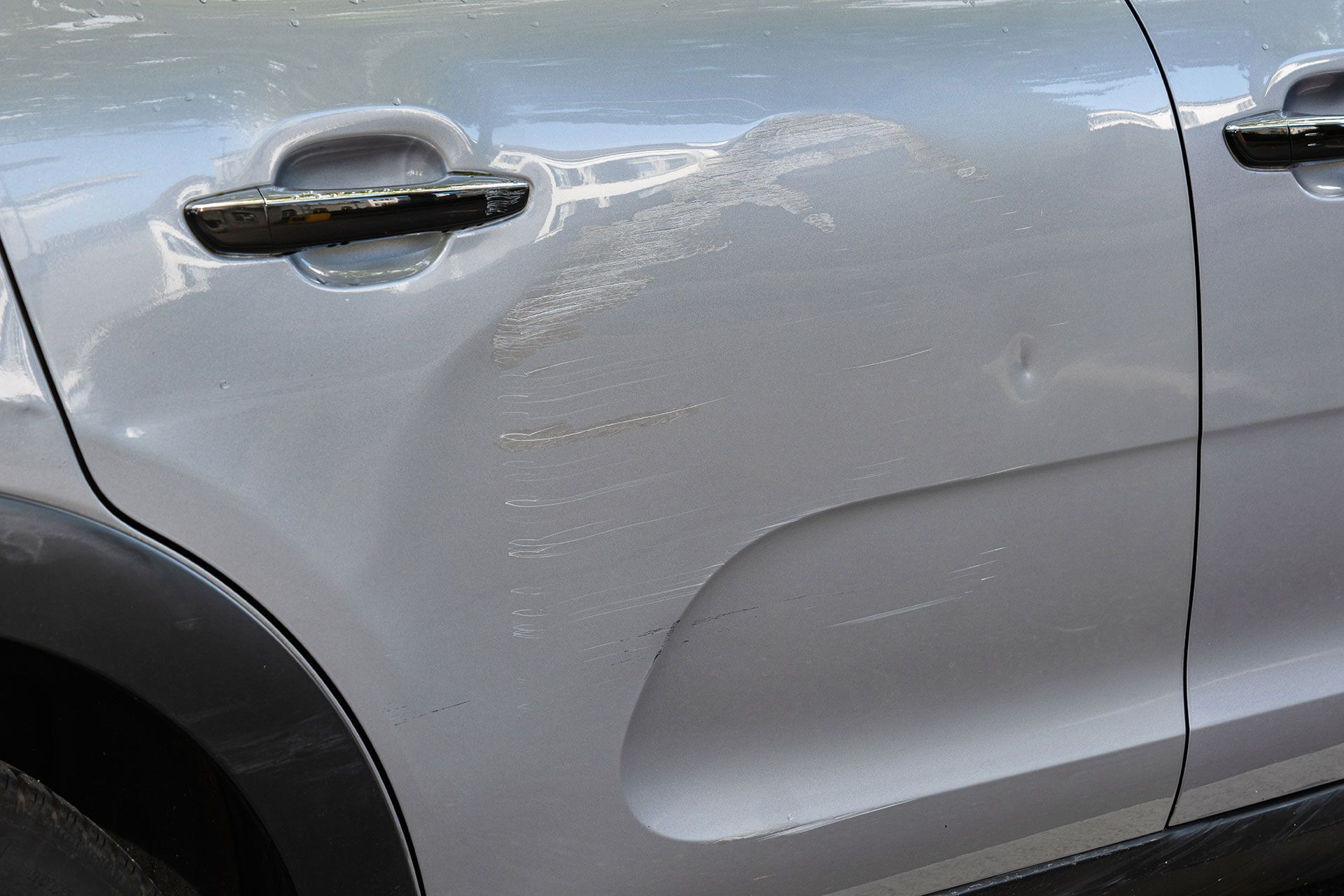 Gray car door with dents and scratches.