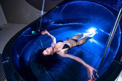 A woman in a bikini is floating in a bathtub.