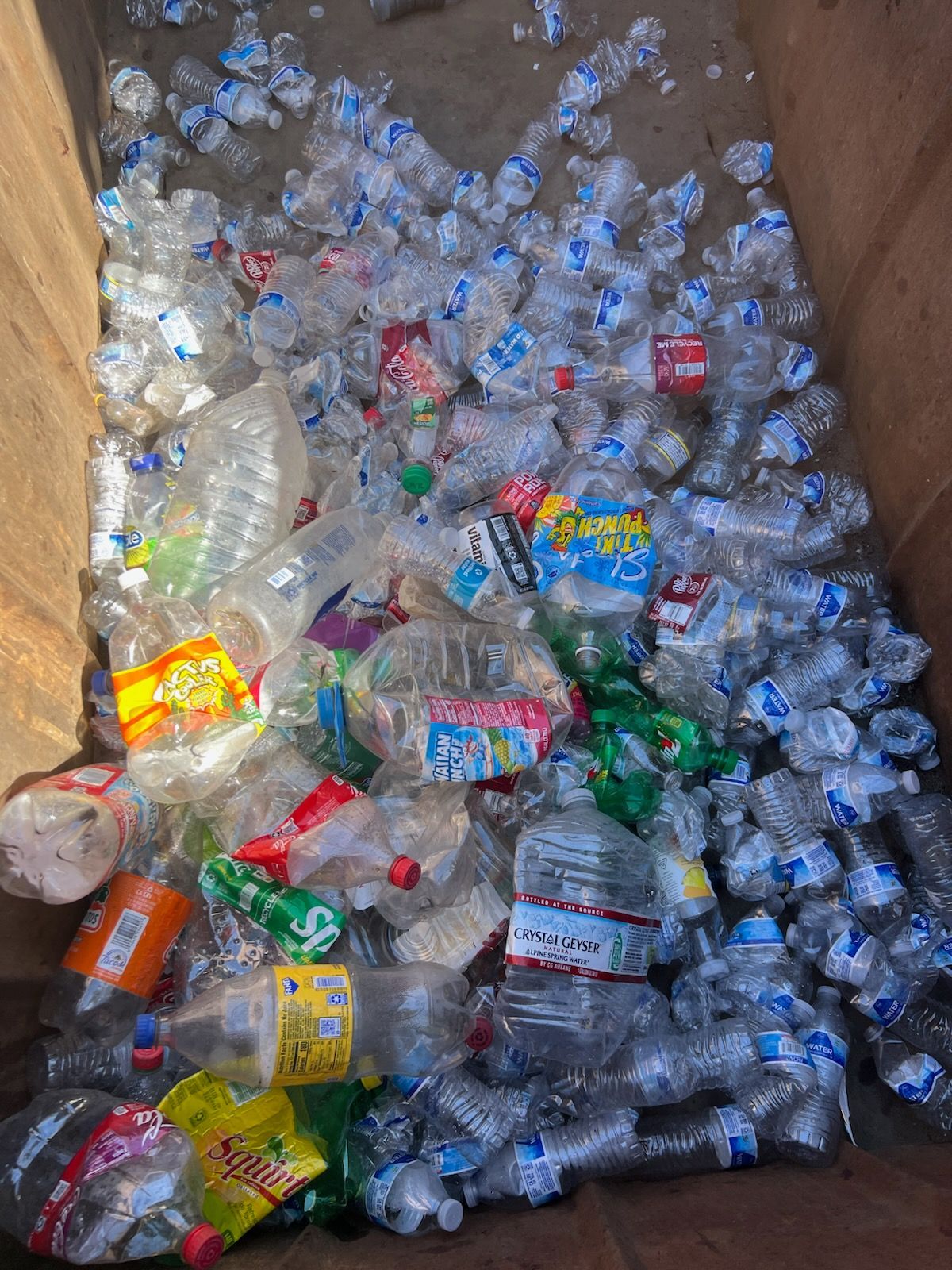 A pile of plastic bottles in a trash can.